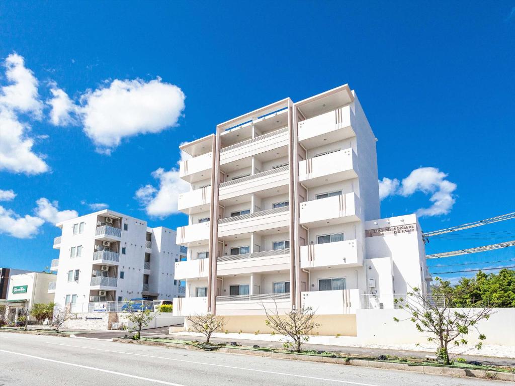 um edifício de apartamentos branco ao lado de uma rua em Little Island Okinawa Nago em Nago