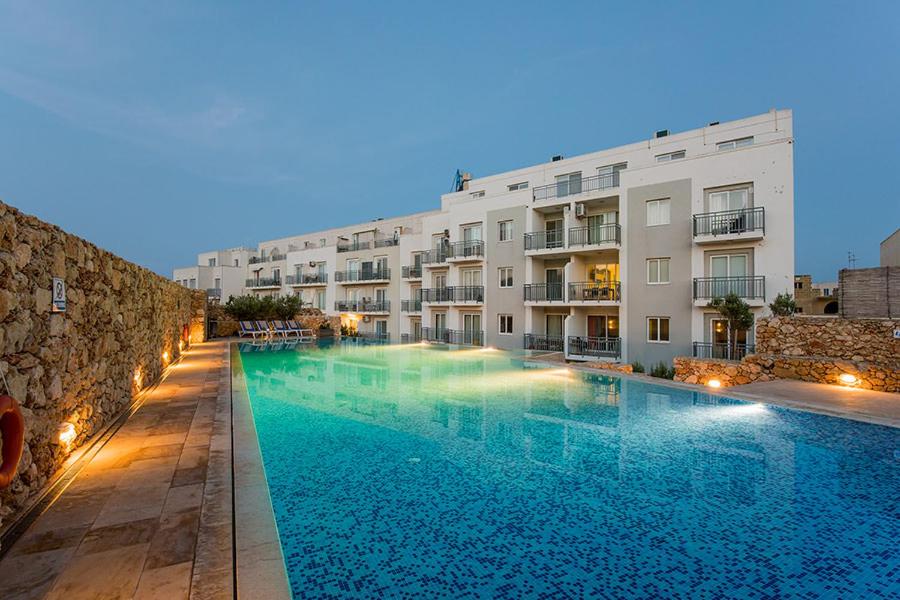 a large swimming pool in front of a building at Hillock Residence Gozo Marsalforn in Marsalforn