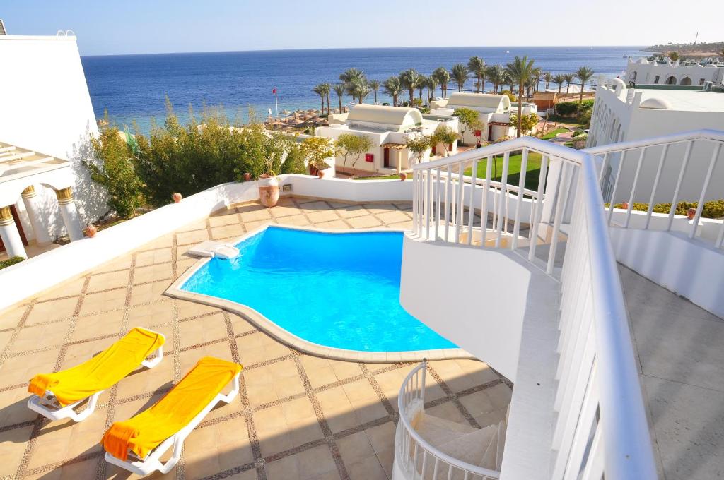 vistas a una piscina con 2 sillas y al océano en Carlton Luxury Villa en Sharm El Sheikh