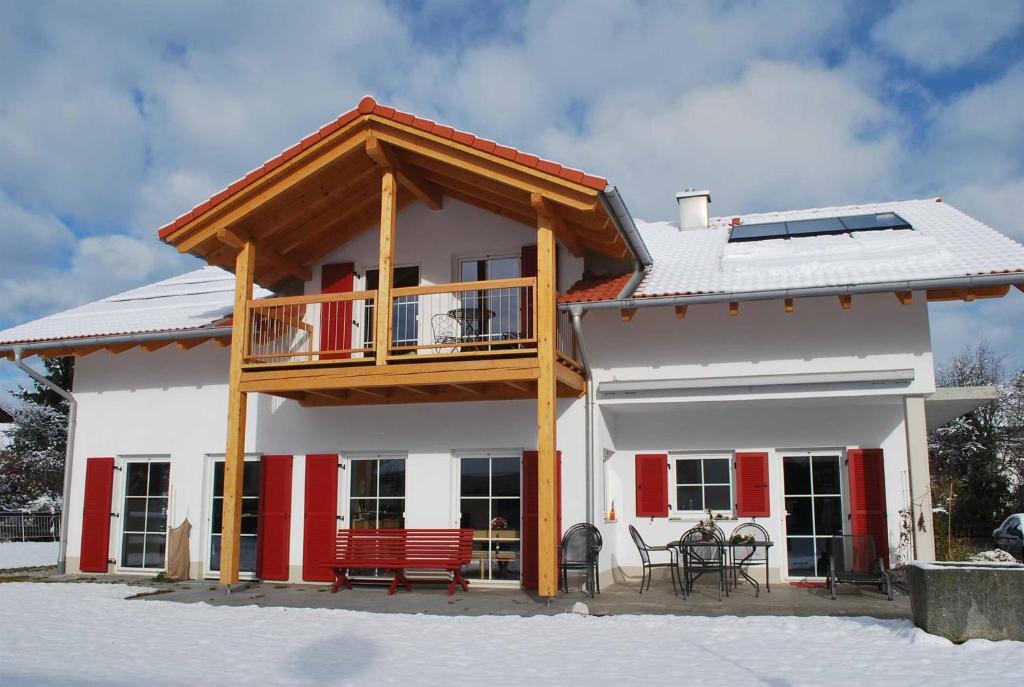 a house with a balcony and red benches in the snow at Ruheoase am Forggensee in Rieden am Forggensee