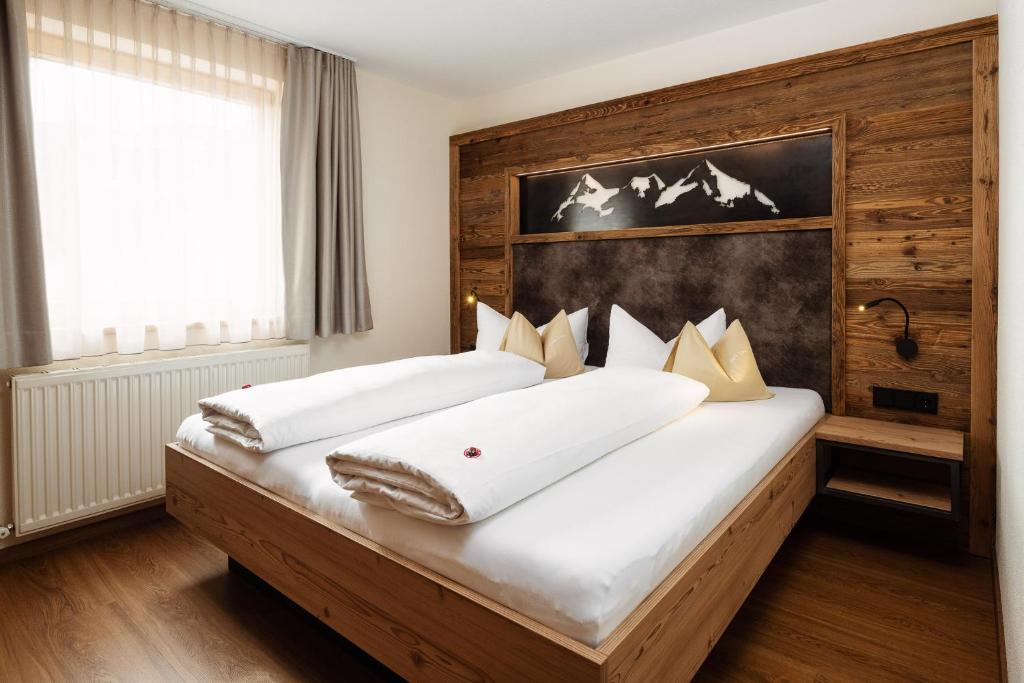 a bedroom with a large bed with a wooden headboard at Apart Garni Hax'n Tenne in Serfaus