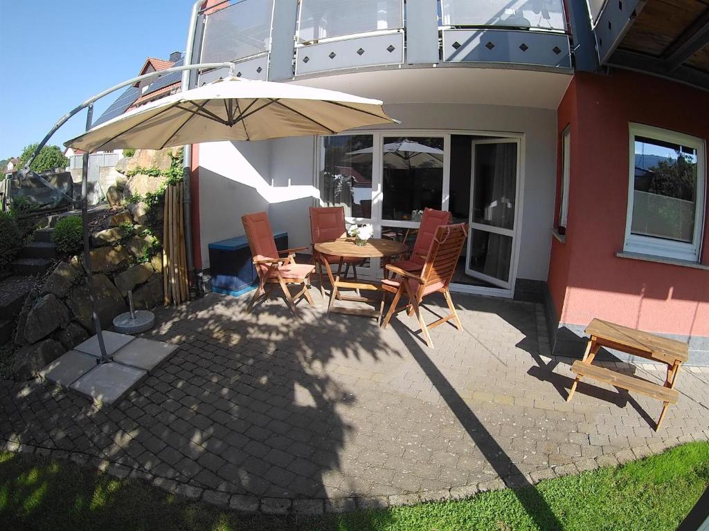 un patio con mesa, sillas y sombrilla en Ferienwohnung Pusteblume, en Ehrenberg