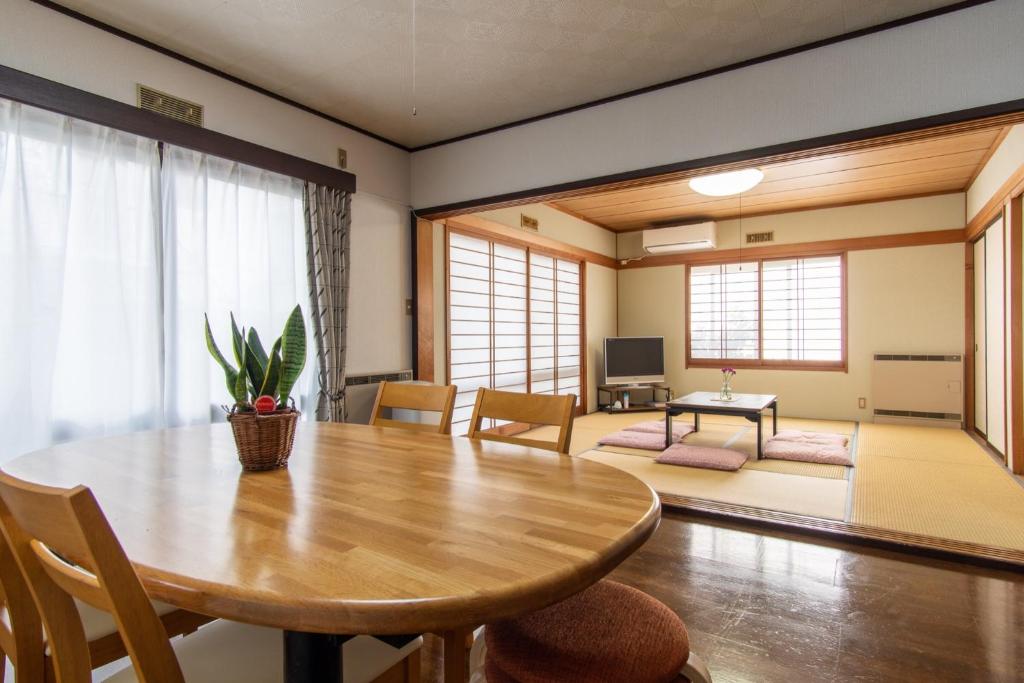une salle à manger avec une table en bois et un salon dans l'établissement Guest house Fujinoyado Akebono - Vacation STAY 92428, à Fujiyoshida