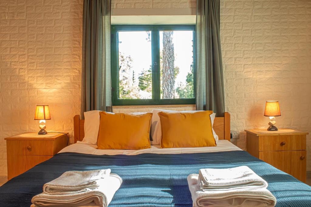 a bedroom with a bed with orange pillows and a window at New Okella Hotel at Saittas in Saittas