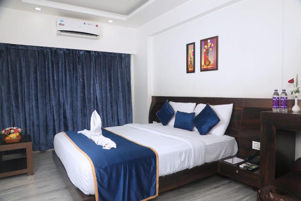 a bedroom with a large bed with blue and white pillows at Hotel Planet Four in Lonavala