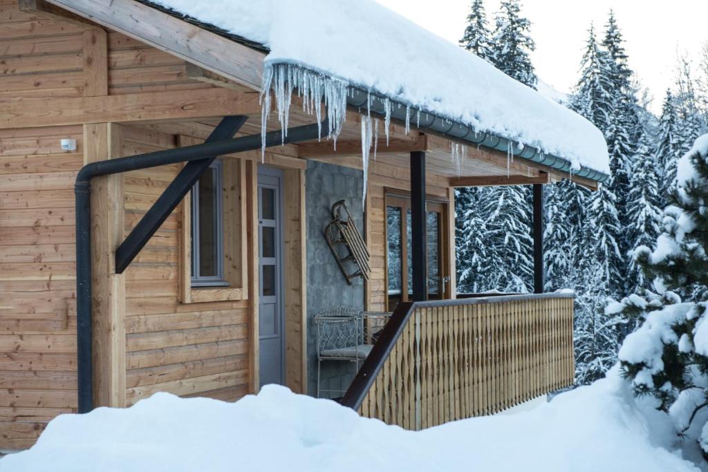 a cabin with icicles hanging from the roof in the snow at Riverwood Lodge in Montriond