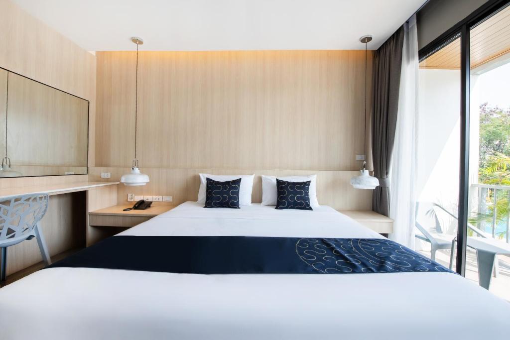 a hotel room with a large bed and a window at Blooming Hill Boutique Suites in Pattaya South
