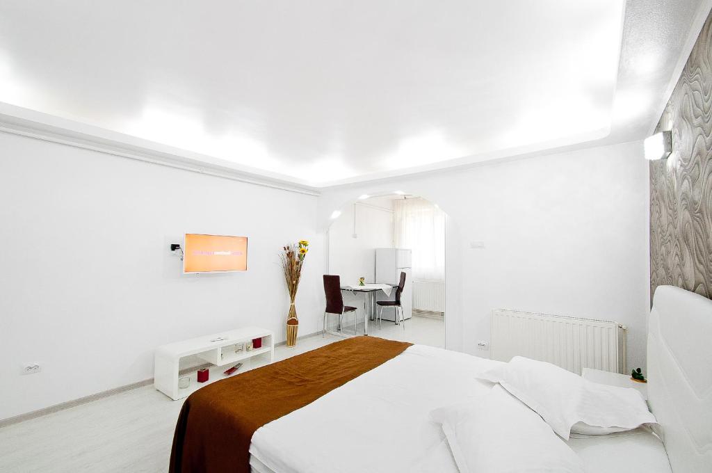 a white bedroom with a bed and a table at Darin Aparthotel in Galaţi