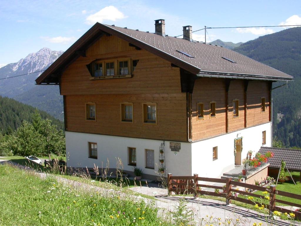 a large wooden house with mountains in the background at Jakoberhof- Bergeweise Urlaubsfeeling in Untertscheltsch