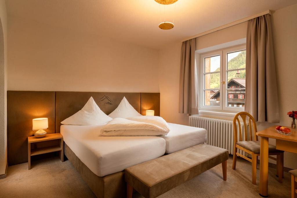 Schlafzimmer mit einem Bett, einem Fenster und einem Tisch in der Unterkunft Murrmel Apartments in Sankt Anton am Arlberg