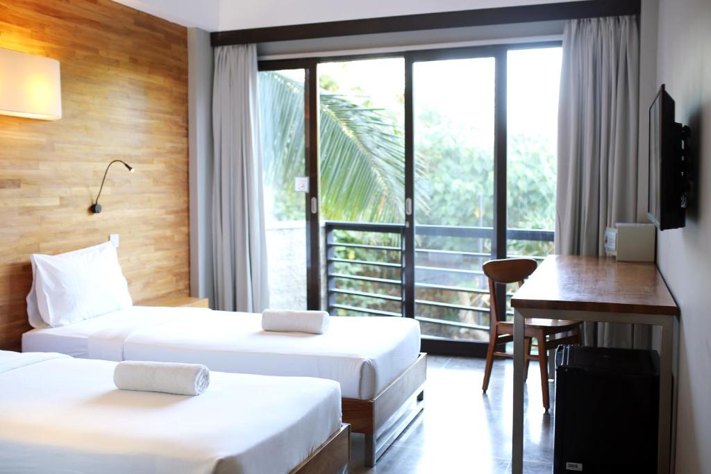 a hotel room with two beds and a desk and a window at Surf Motel in Canggu