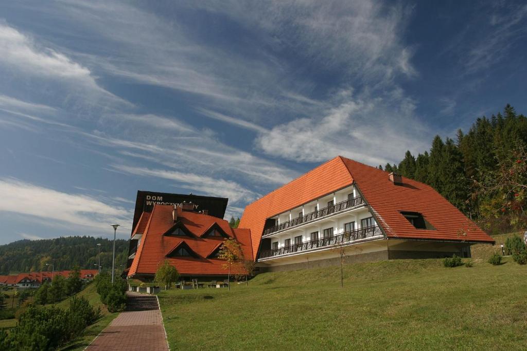 a building with an orange roof in a field at Dom Wypoczynkowy Pod Taborem in Niedzica Zamek