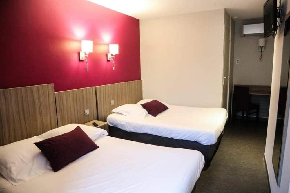 een hotelkamer met 2 bedden en een rode muur bij HOTEL DU COMMERCE in La Châtre
