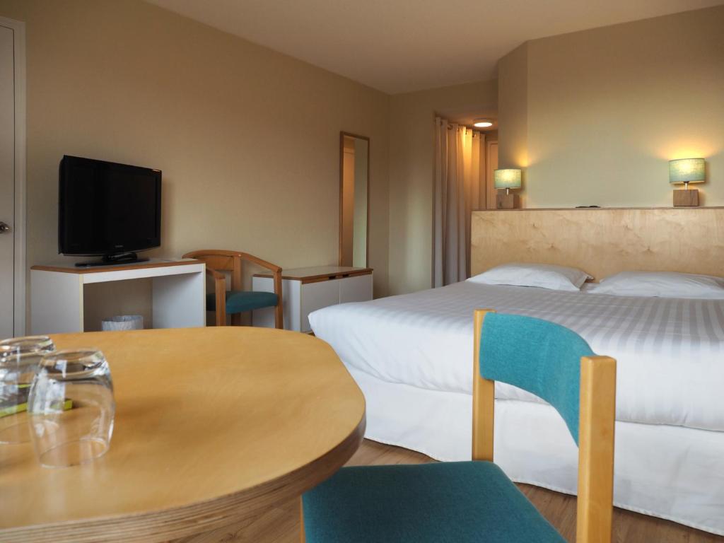 a hotel room with two beds and a table and chairs at Logis Hôtel du Belvédère in Brest