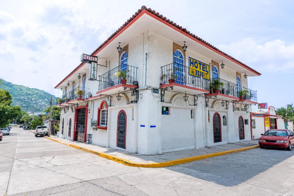 a white building with blue windows on a street at Hotel Isis in Zihuatanejo