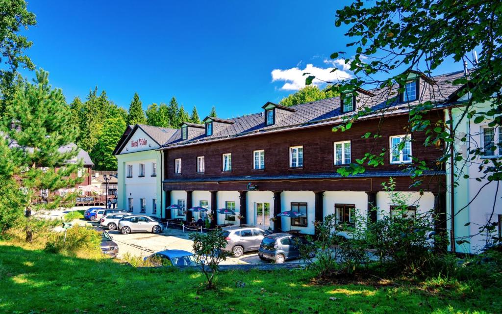 uma casa grande com carros estacionados em frente em Hotel Džbán em Karlova Studánka