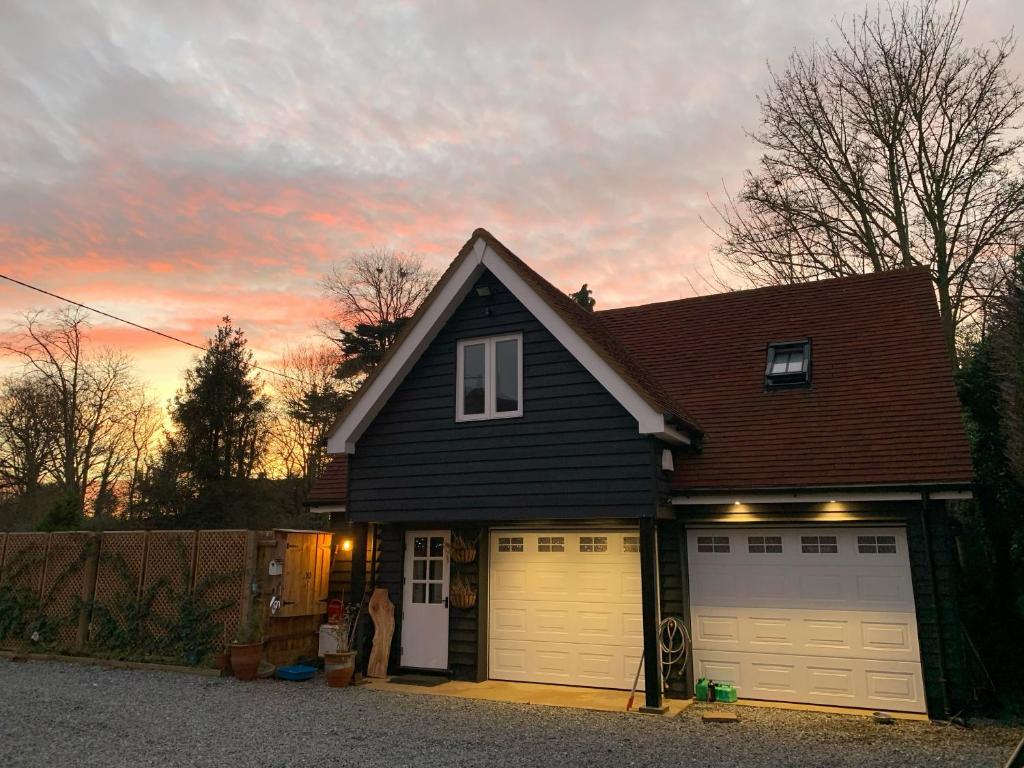 a house with two garage doors and a sunset at The Cottage get away in Saffron Walden