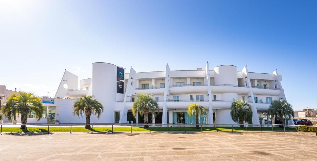 a white building with palm trees in front of it at Callistos Hotel & Spa in Tricase