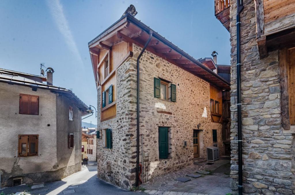 an old stone building with green shutters on a street at Maso Pejo in Peio