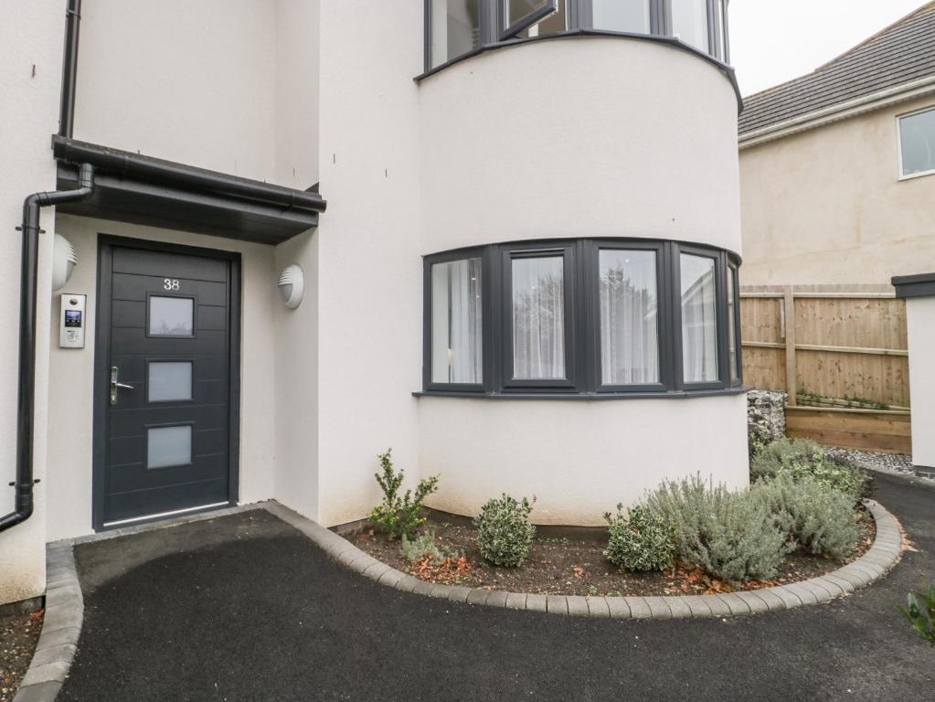 a house with a black door and a driveway at Flat 2, 38 Preston Road in Weymouth