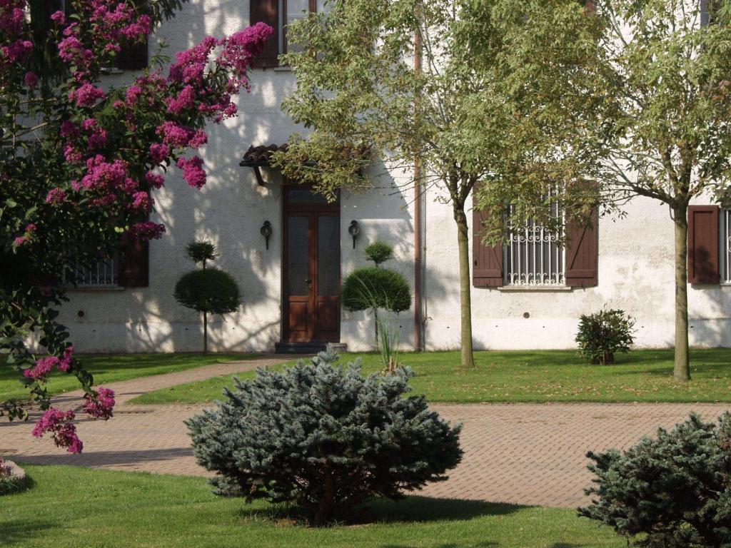 una casa blanca con una puerta y árboles y flores en B&B Casa Manuelli, en Alessandria