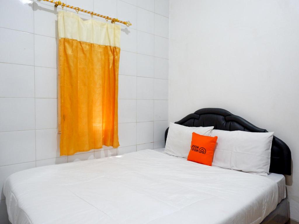 1 dormitorio con 1 cama y ventana de color naranja en KoolKost Syariah near Universitas Diponegoro Tembalang 2, en Srondolwetan