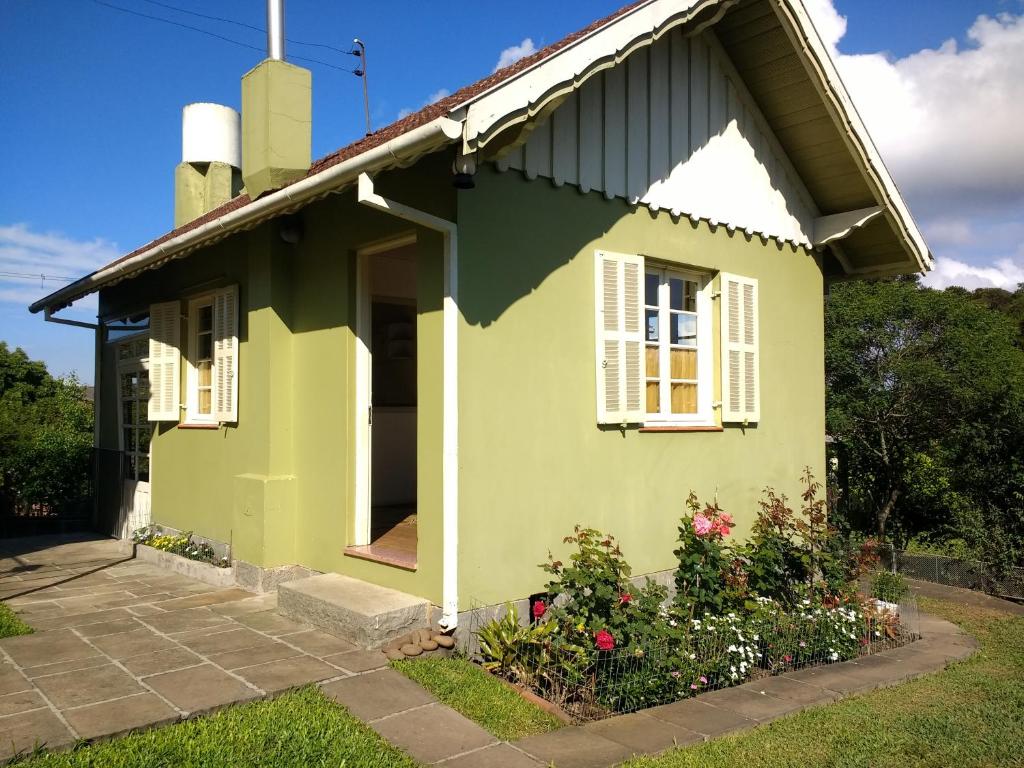 una casa verde con ventanas blancas y flores en Cabana Canela, en Canela
