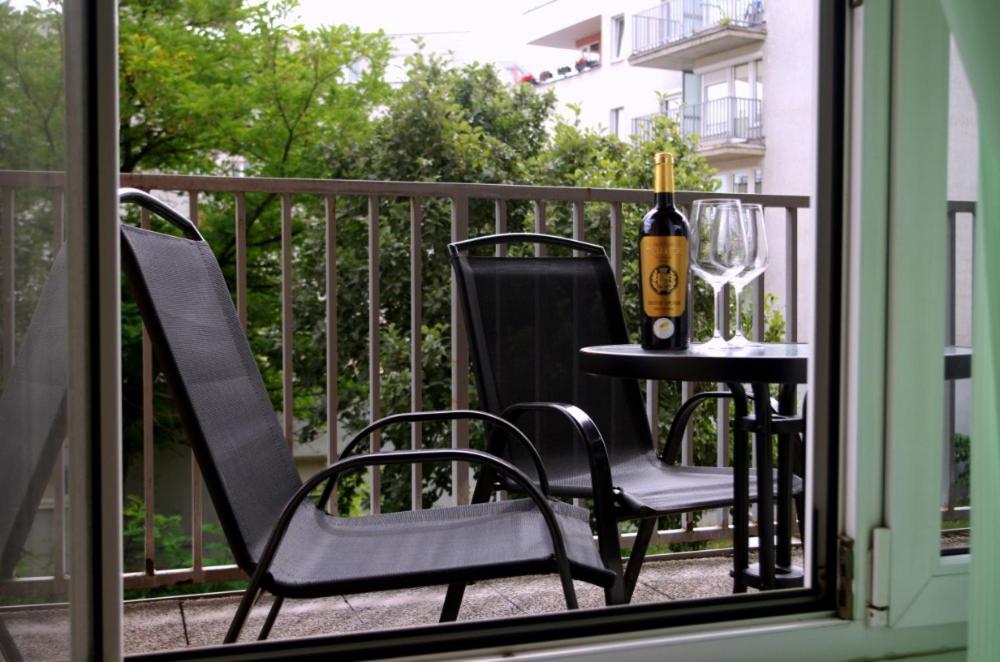 uma mesa com uma garrafa de vinho e 2 cadeiras numa varanda em apartment golden Prague em Praga