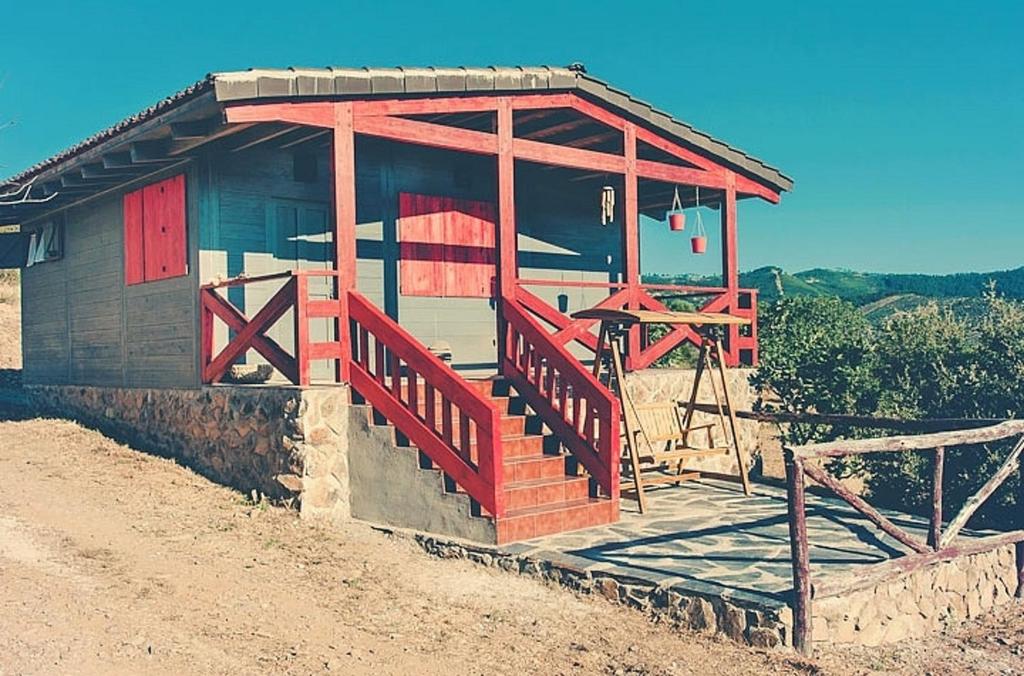 a small wooden building with a red door and stairs at Charming house in Cañamero with pool and mountain view in Cañamero