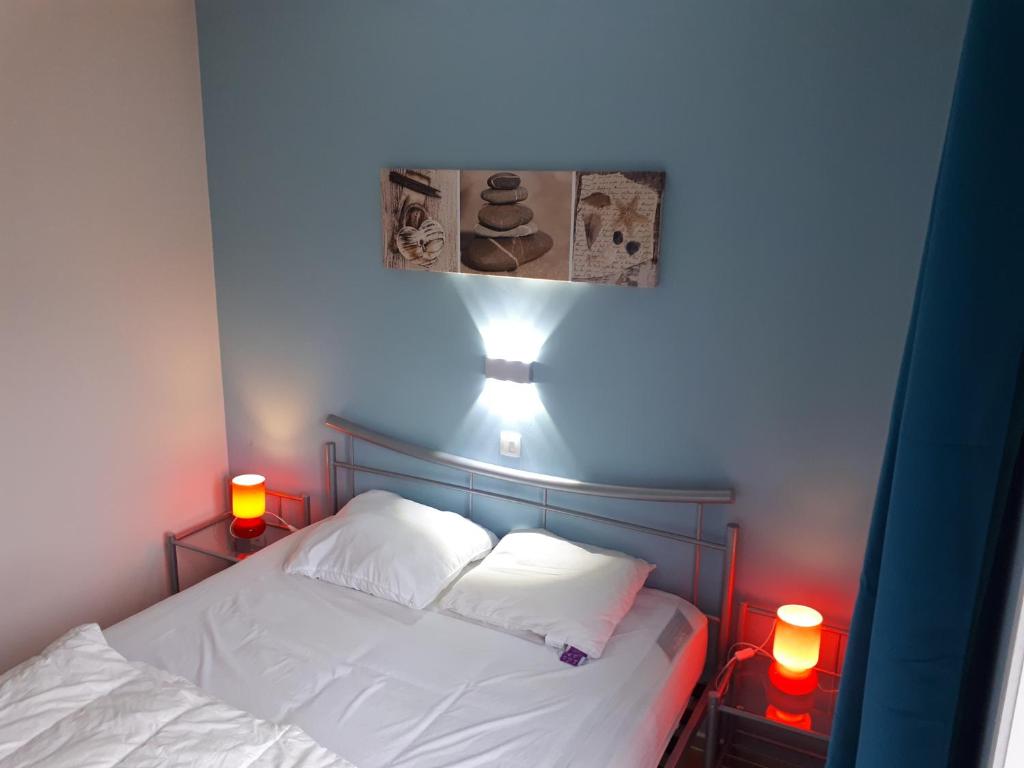 a bedroom with a bed with two pillows and two lights at Résidence Jersey (app. 201) in Koksijde