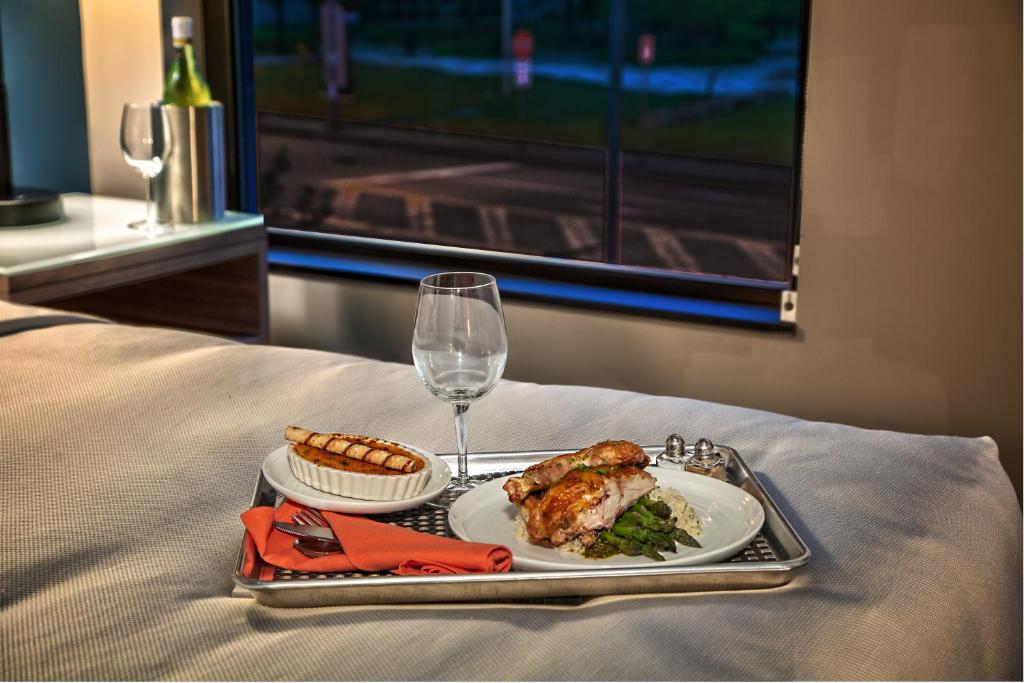 a tray with a plate of food and a glass of wine at Hotel Indigo Pittsburgh University - Oakland, an IHG Hotel in Pittsburgh