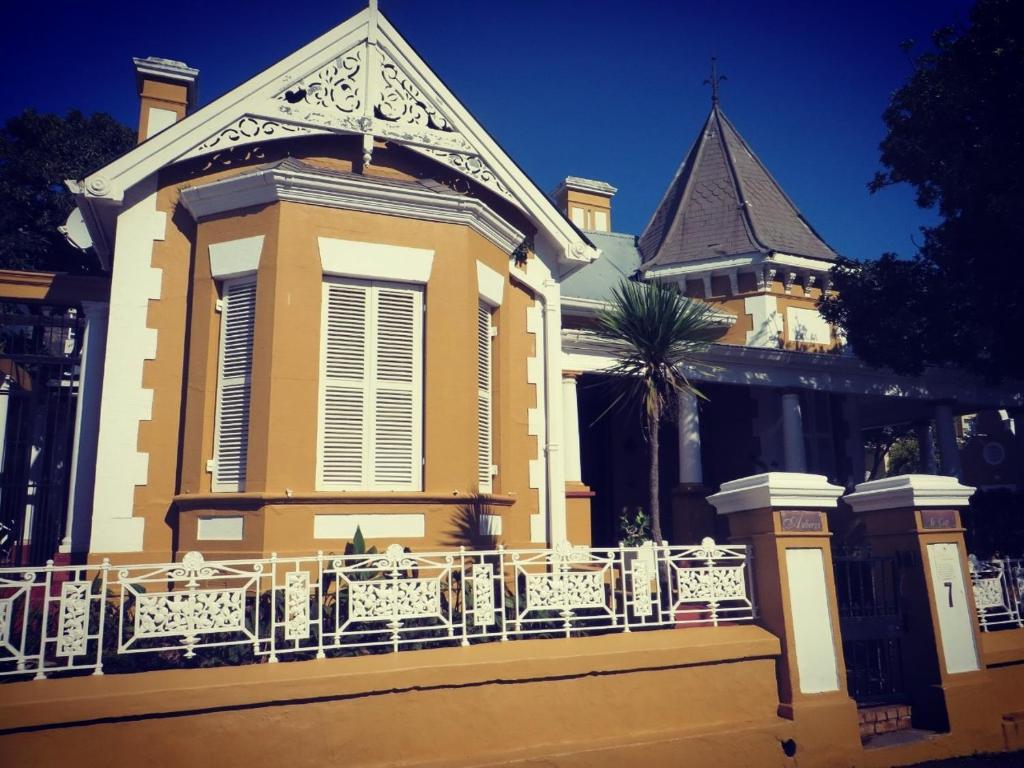 a yellow building with a balcony and a clock tower at Ashanti Gardens Guesthouse in Cape Town