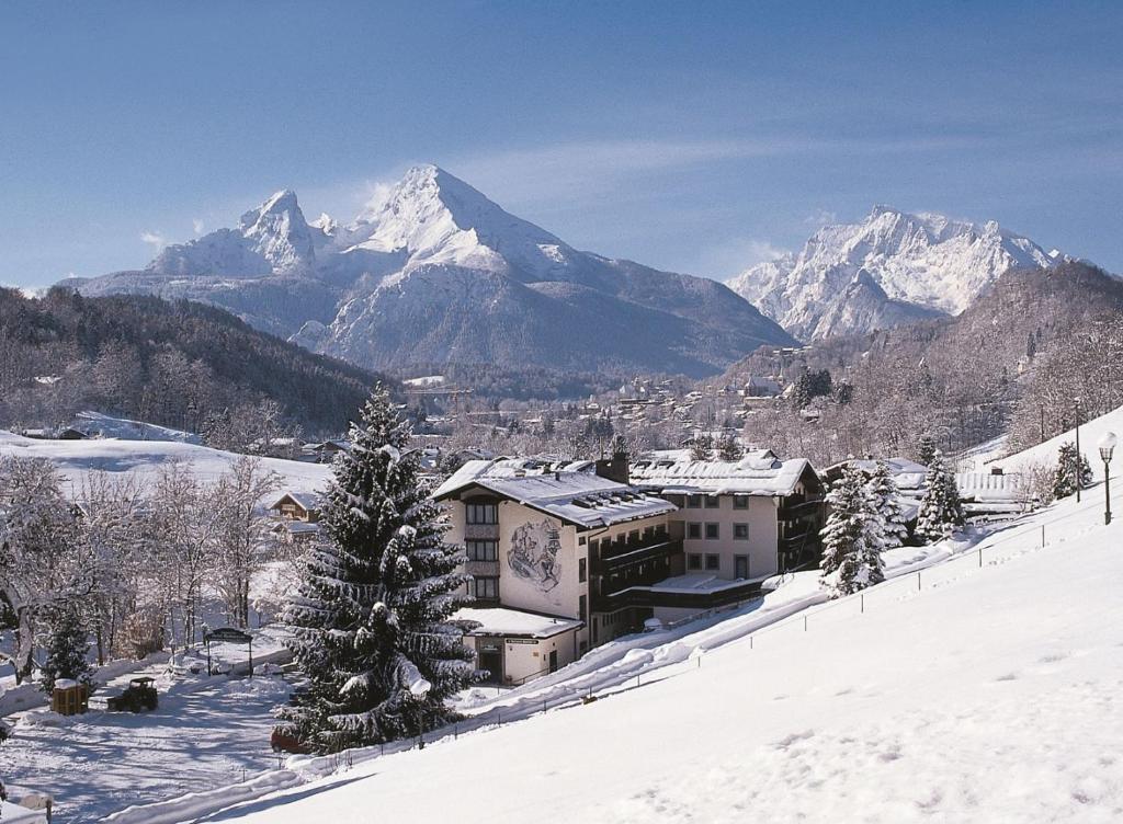 un complexe dans la neige avec une montagne en arrière-plan dans l'établissement Alpen-Hotel Seimler, à Berchtesgaden