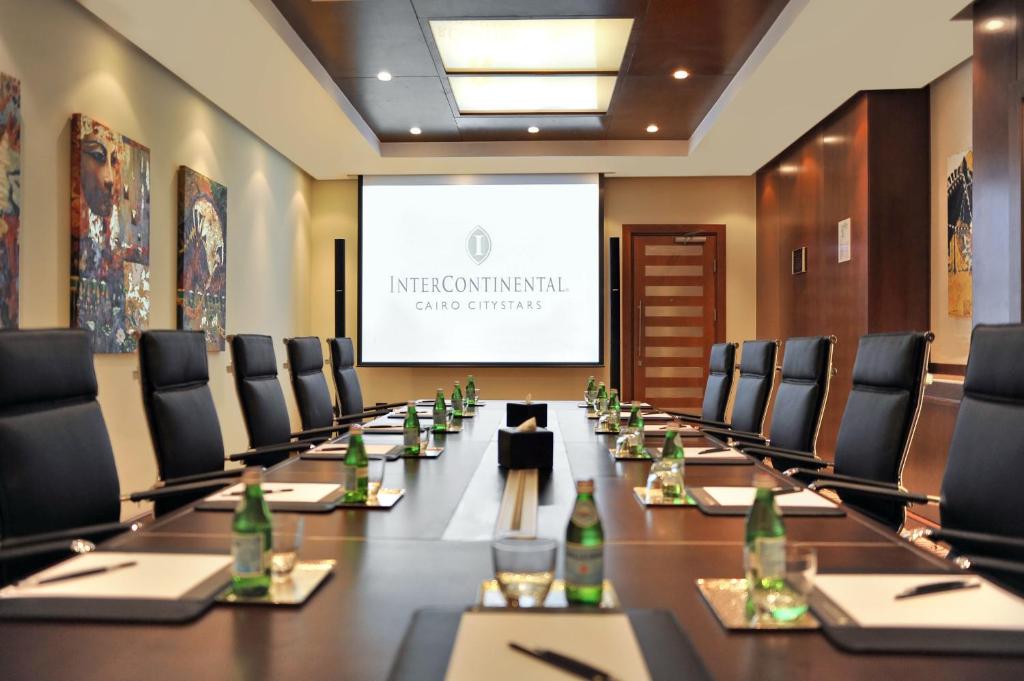 a boardroom with a long table and chairs and a screen at Intercontinental Cairo Citystars by IHG in Cairo