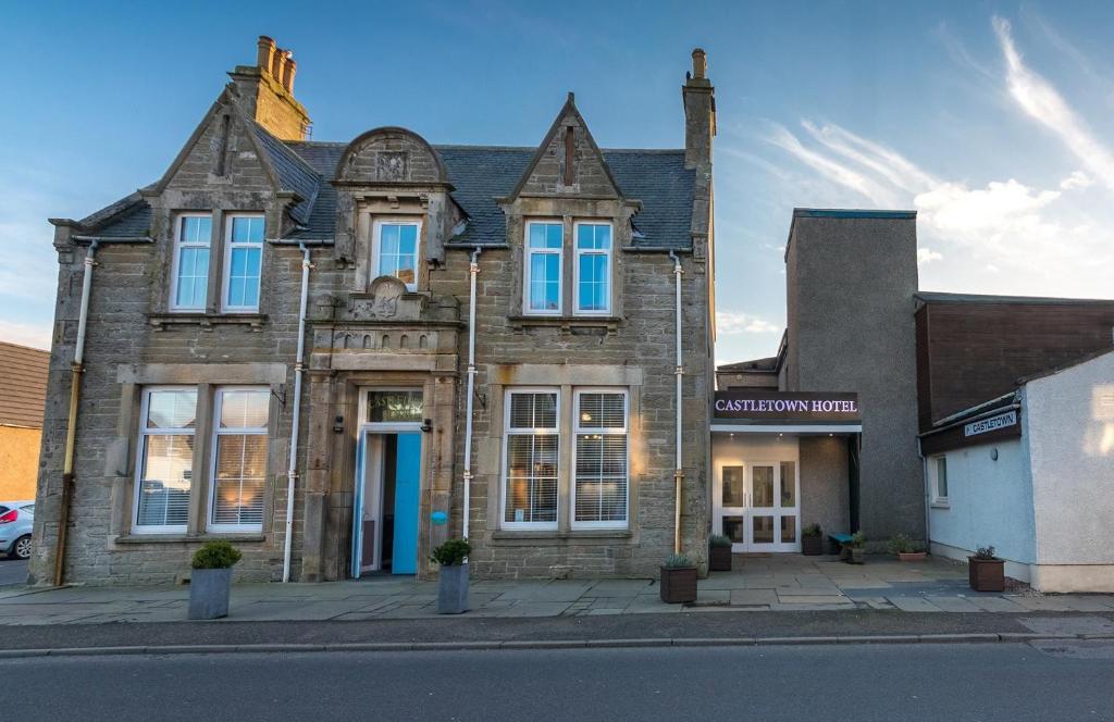 an old building on the corner of a street at Castletown Hotel in Castletown