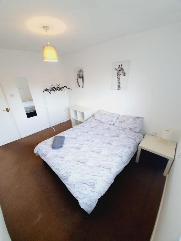 a bedroom with a white bed and a table at 2 Bedroom Rayleigh Apartment in Rayleigh