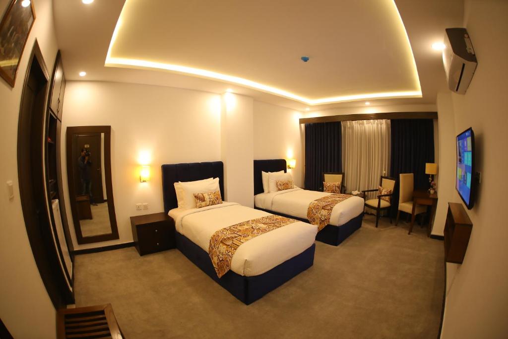 a hotel room with two beds and a television at Grand Mongolia Hotel in Rawalpindi