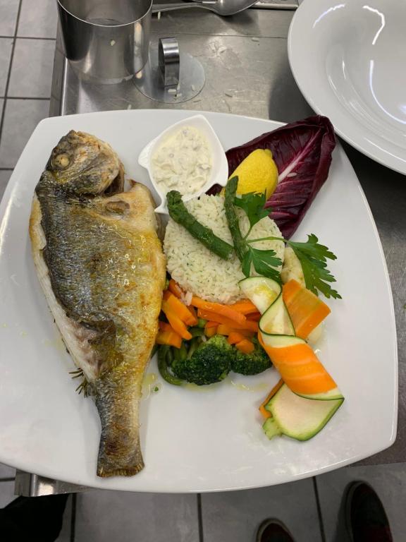 un plato de comida con pescado y verduras. en Ristorante Con alloggio Val Sole, en Acquarossa