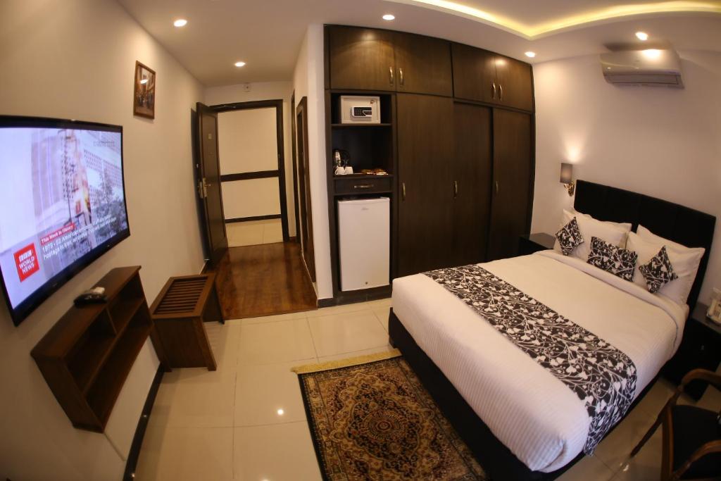 a bedroom with a bed and a flat screen tv at Grand Mongolia Hotel in Rawalpindi