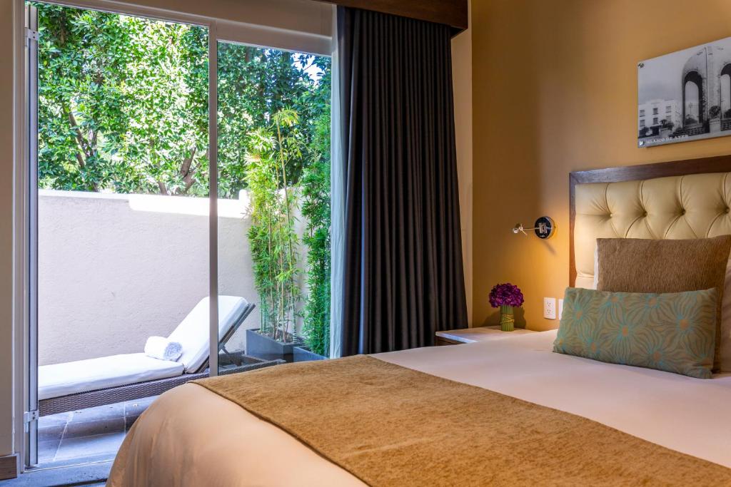 a bedroom with a bed and a large window at Casa Malí by Dominion Boutique Hotel in Mexico City