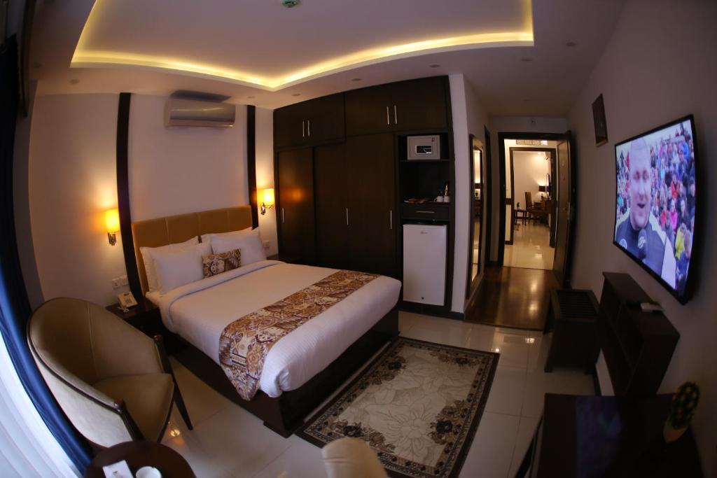 a hotel room with a bed and a television at Grand Mongolia Hotel in Rawalpindi