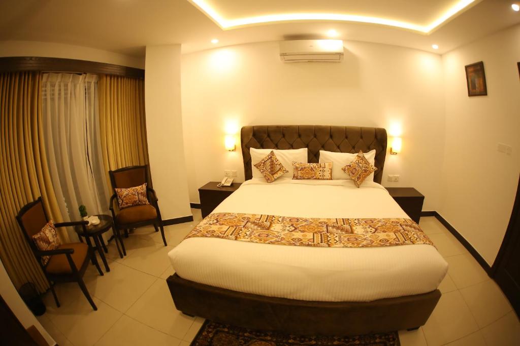 a hotel room with a bed and two chairs at Grand Mongolia Hotel in Rawalpindi