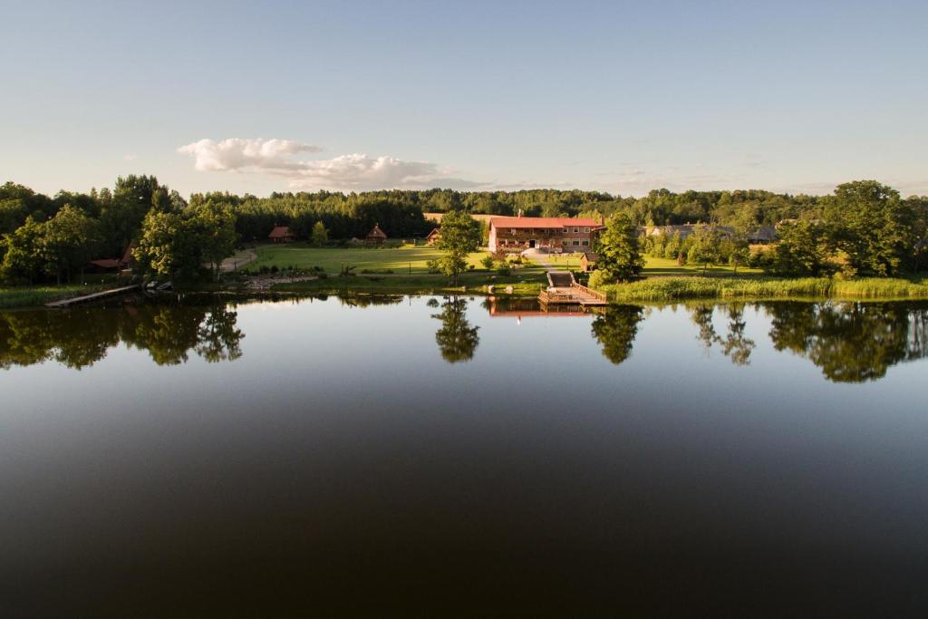 a view of a lake with a house in the background at Vila Karališkis in Karališkiai