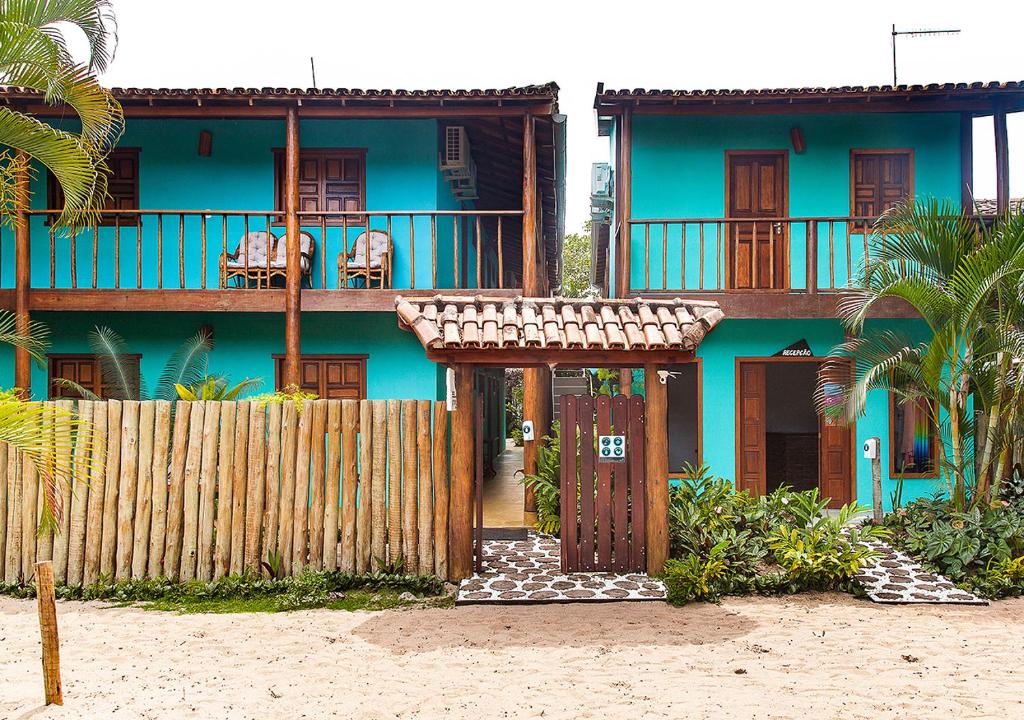 a blue house with a fence in front of it at Pousada Jambrero in Caraíva