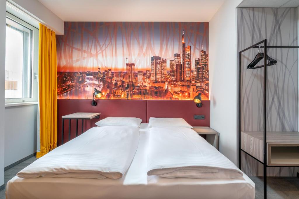 um quarto com uma cama grande com um pano de fundo da cidade em Campanile Frankfurt Offenbach em Offenbach