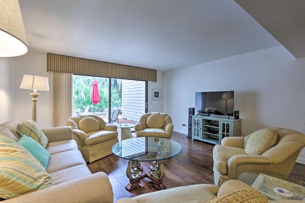 uma sala de estar com sofás, uma mesa e uma televisão em Shipyard Villa with Golf Course Views and Beach Access em Hilton Head Island