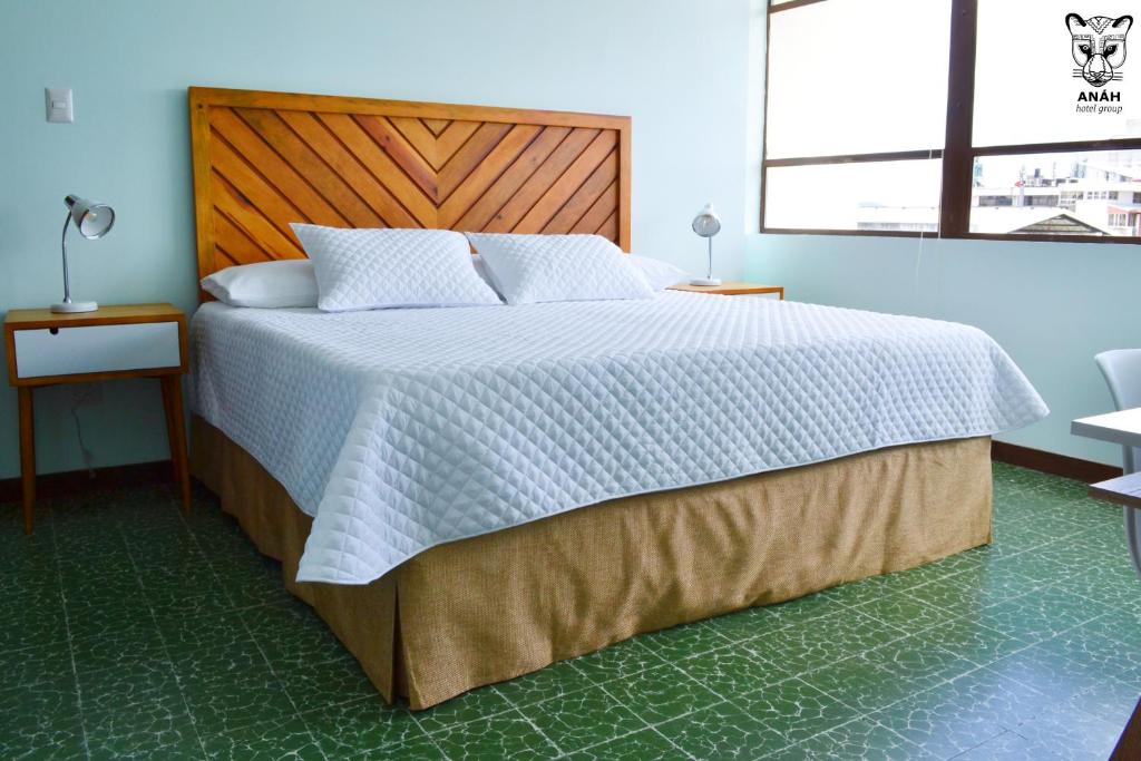 a bedroom with a large bed with a wooden headboard at Apartamentos el Prado en Zona 1 - ANAH hotel group in Guatemala
