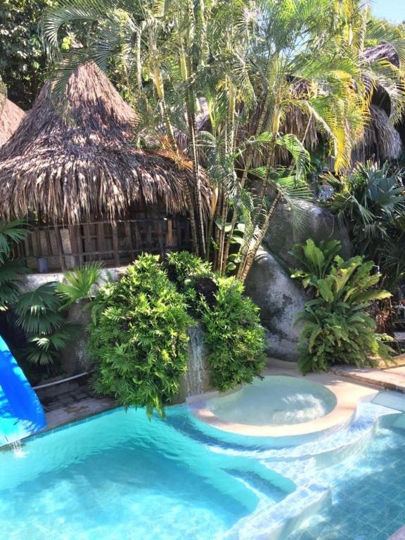 un complejo con piscina y techo de paja en Eco Hostal Yuluka, en El Zaino