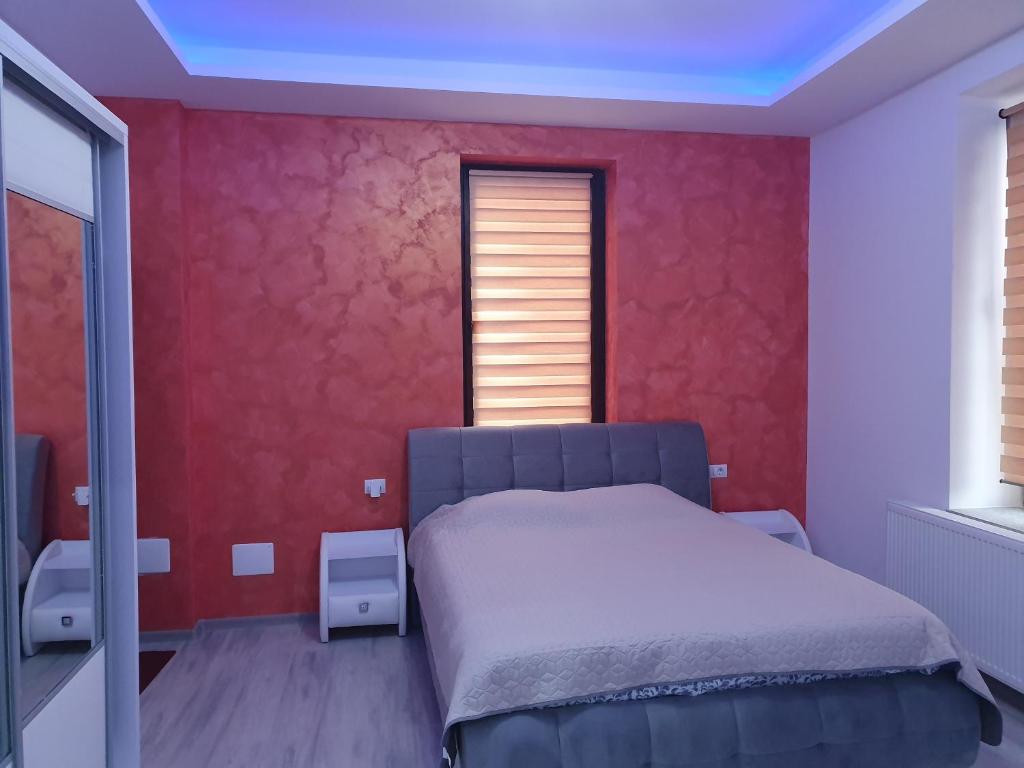 een slaapkamer met een bed en een rode muur bij negris2 in Bîrlad