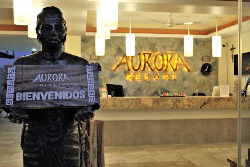 a statue holding a sign in front of a restaurant at Aurora Resort in Rincon de Guayabitos